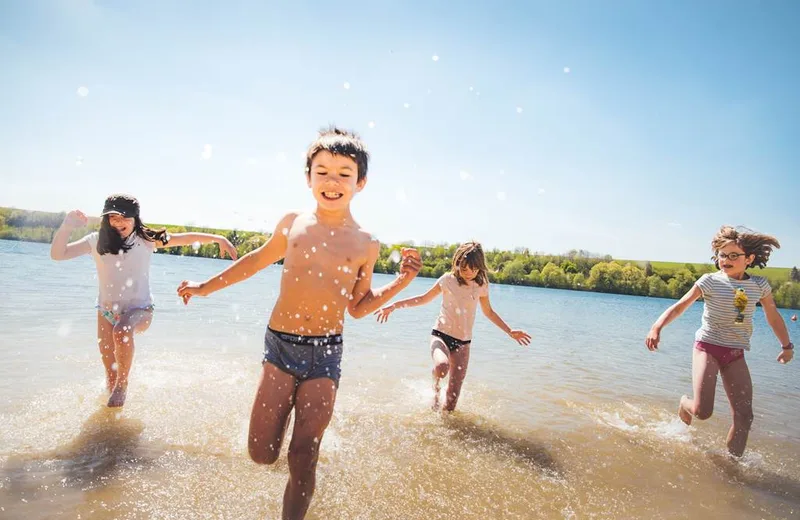 Enfants qui jouent dans l'eau au bordde la plage du Lac de Bairon